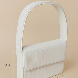 a white shoulder bag with dimensions provided in inches.
