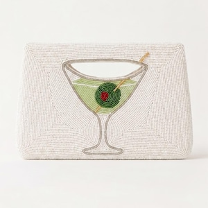 K&ouml;nnte beinhalten: Wei&szlig;es Perlen-Etui mit Martini-Glas-Design. Das Glas ist mit gr&uuml;ner Fl&uuml;ssigkeit und einer rot-zentrierten Olive gef&uuml;llt. Die Clutch hat eine rechteckige Form und einen silberfarbenen Umriss.