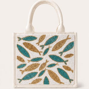 May include: Off-white tote bag with a beaded fish design. The bag features a white background with teal and gold fish patterns. The bag has a sturdy handle and a rectangular shape.