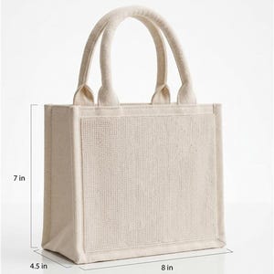 May include: A beige mini tote bag with two top handles and a textured front panel. The bag features text reading mini tote DIMENSIONS and includes measurement lines indicating a height of 7 inches, a width of 8 inches, and a depth of 4.5 inches.