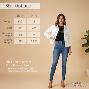 a woman wearing a white jacket and blue jeans, standing in front of a size chart.