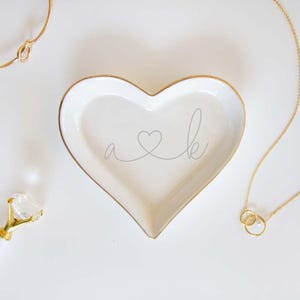 a heart shaped dish with a couple's initials on it