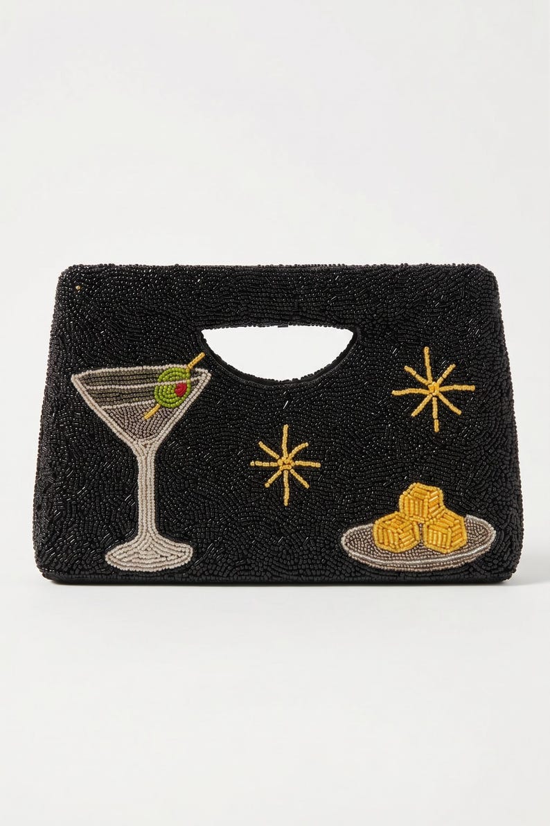 K&ouml;nnte beinhalten: Schwarze, perlenbesetzte Clutch mit Henkel, mit einem Martiniglas mit Olive, Sternen und einem Teller mit Vorspeisen. Die Clutch hat eine rechteckige Form mit einem ausgeschnittenen Henkel.