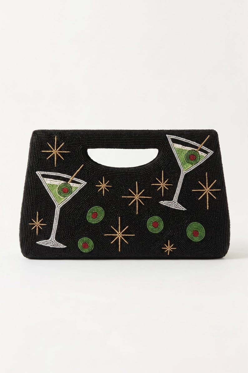K&ouml;nnte beinhalten: Schwarze, perlenbesetzte Handtasche mit Martini-Gl&auml;sern und Sternenmustern. Die Martini-Gl&auml;ser sind gr&uuml;n mit roten Oliven-Akzenten. Die Tasche hat einen Griff und ist mit goldenen und wei&szlig;en Perlen verziert.