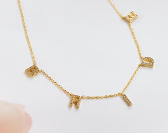 May include: A gold chain necklace with the word "BRID" spelled out in small, sparkly letters.