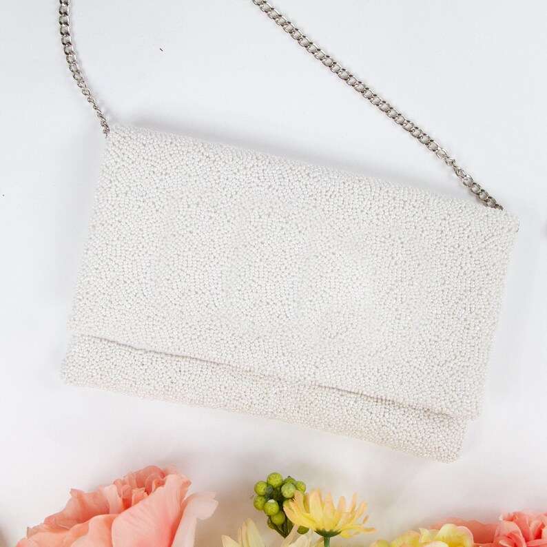 a white purse sitting on top of a table next to flowers