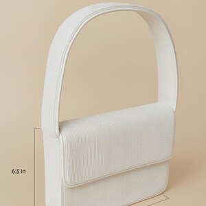 a white shoulder bag with dimensions provided in inches.