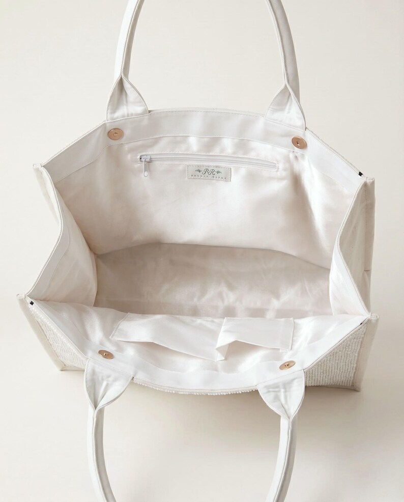 A white tote bag with a zipper and handles, open to reveal the interior.