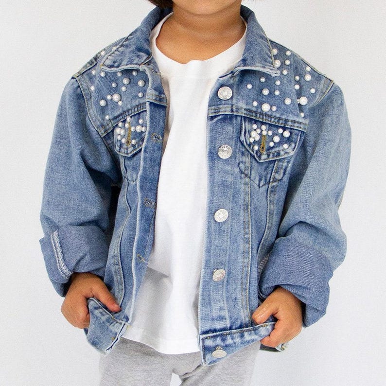 a little girl wearing a jean jacket and white shirt