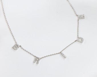 May include: A silver chain necklace with the word "BRIDE" spelled out in small, sparkly letters.