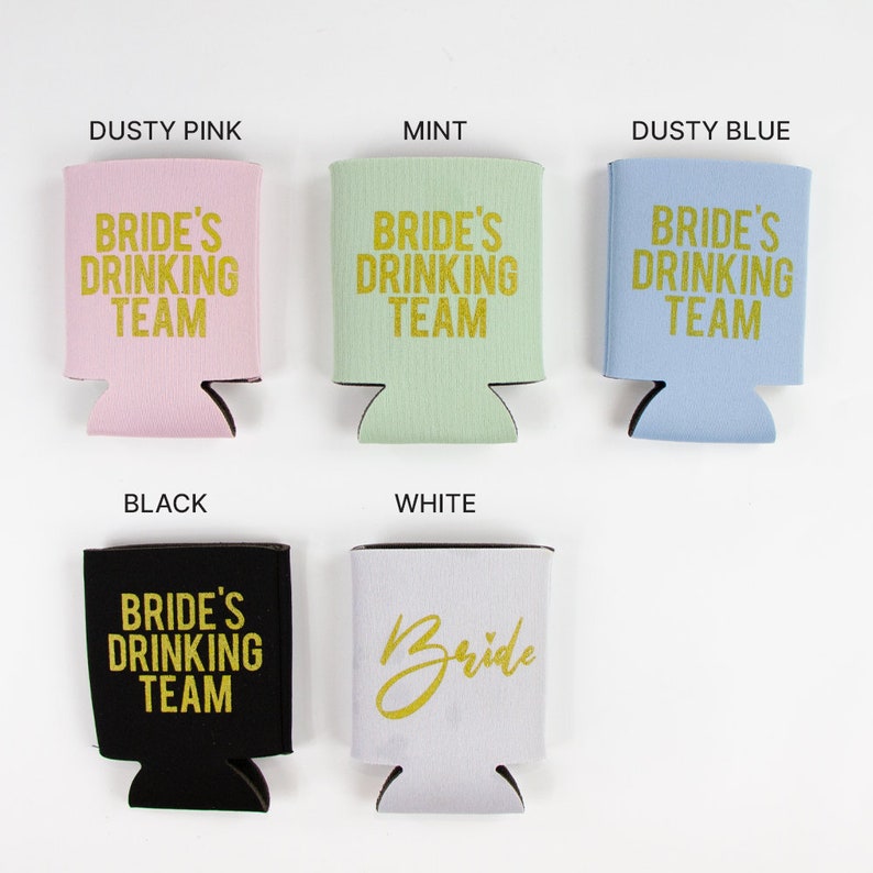 May include: Six different colored can coolers with the text "Bride's Drinking Team" in gold lettering. The colors are dusty pink, mint, dusty blue, black, white, and a light gray.