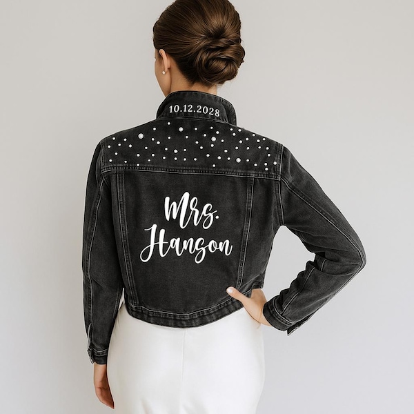 May include: A black denim jacket featuring white pearl embellishments across the upper back and shoulders. The collar displays the text 10.12.2028 in white, while the center back features the white script text Mrs. Hanson.