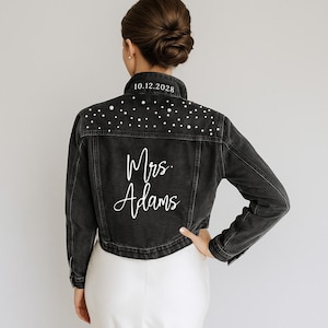 A woman wearing a black denim jacket with white polka dots and the text "Mrs. Adams" printed on the back.