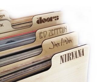 Puede incluir: Un organizador de almacenamiento de discos de madera con cinco ranuras. Cada ranura tiene un nombre de banda diferente grabado en él: The Doors, Led Zeppelin, Jimi Hendrix y Nirvana.