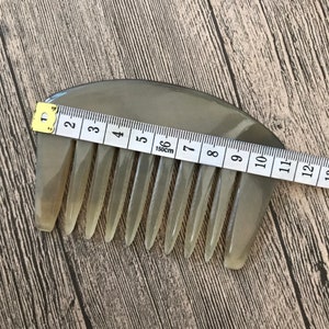 K&ouml;nnte beinhalten: Ein hellbrauner, halbmondf&ouml;rmiger Kamm mit einer Reihe von Z&auml;hnen. Der Kamm ist 15 cm lang und wird mit einem Ma&szlig;band gemessen.
