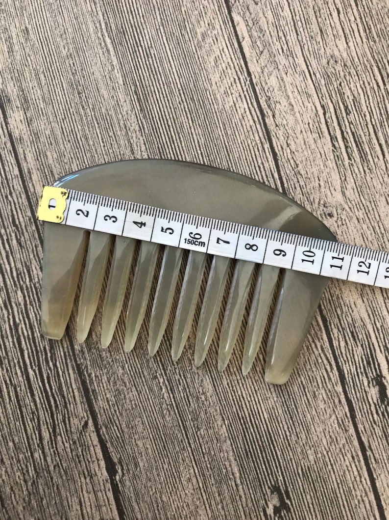 K&ouml;nnte beinhalten: Ein hellbrauner, halbmondf&ouml;rmiger Kamm mit einer Reihe von Z&auml;hnen. Der Kamm ist 15 cm lang und wird mit einem Ma&szlig;band gemessen.