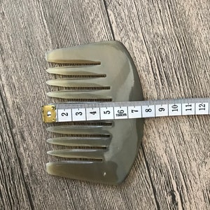 K&ouml;nnte beinhalten: Ein hellbrauner Kamm aus Horn mit abgerundetem Griff. Der Kamm ist 15 cm lang und hat 10 Z&auml;hne.