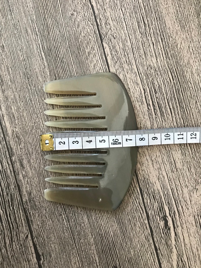 K&ouml;nnte beinhalten: Ein hellbrauner Kamm aus Horn mit abgerundetem Griff. Der Kamm ist 15 cm lang und hat 10 Z&auml;hne.