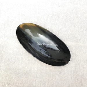 Puede incluir: Un plato ovalado negro hecho de cuerno. El plato es liso y brillante. El texto "Hala Design.vn" está grabado en el plato.