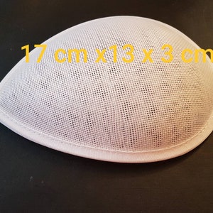 Könnte beinhalten: Ein weißer Hutrohling in Tropfenform, ca. 17 cm lang, 13 cm breit und 3 cm hoch. Der Rohling besteht aus einem gewebten Material und hat einen genähten Rand. Dieser Hutrohling ist für Hutmacherprojekte bestimmt.