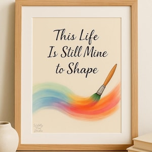 Può includere: Stampa artistica incorniciata con la scritta "This Life Is Still Mine to Shape" sopra una colorata pennellata arcobaleno. L'opera presenta un pennello con manico in legno e sfondo beige.