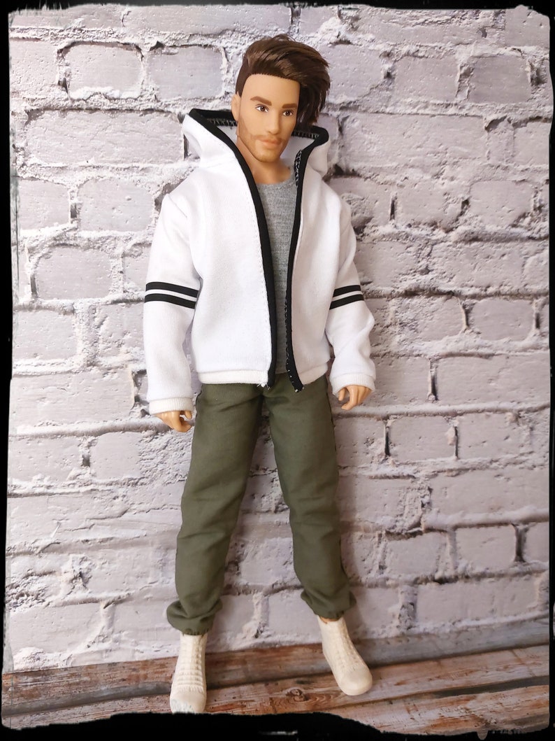 Peut inclure: Un sweat-shirt &agrave; capuche blanc avec des rayures noires sur les manches et une fermeture &eacute;clair noire. Le sweat-shirt est associ&eacute; &agrave; un pantalon vert olive et des baskets blanches.