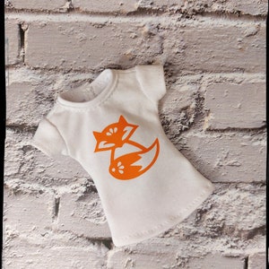 May include: White t-shirt with an orange fox graphic. The fox is curled up with its tail wrapped around its body.