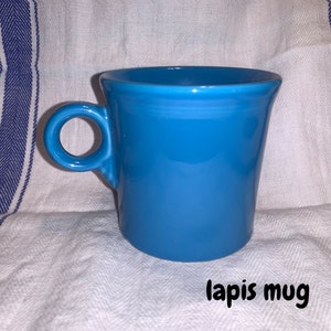 May include: A bright blue ceramic mug with a rounded handle. The mug is labeled "lapis mug".
