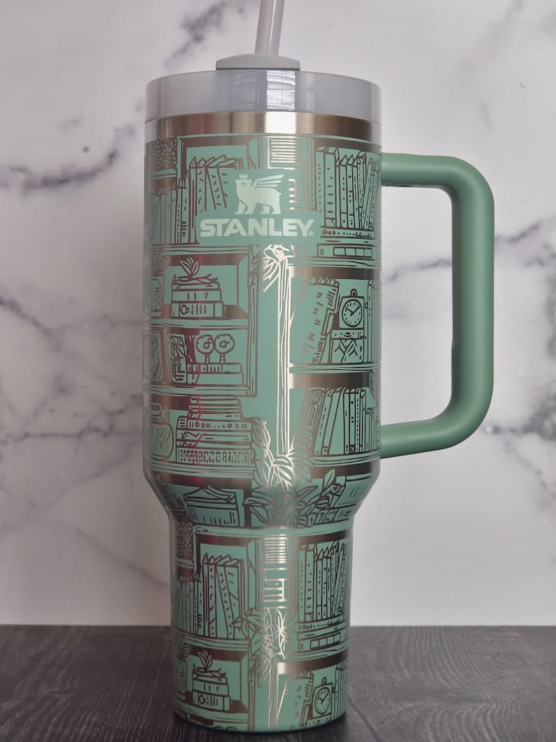 Teal 30 oz Stanley tumbler with laser design of bookshelves.