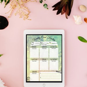 May include: A digital tablet displaying a weekly card reading planner with a colorful background. The planner includes spaces for each day of the week to write down tarot card readings.