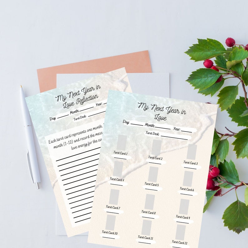 May include: A set of printable tarot card reflection sheets with the text "My Next Year in Love" and spaces to record the day, month, year, and tarot deck. Each sheet has spaces for 12 tarot cards. A white pen and a sprig of red berries are also visible.