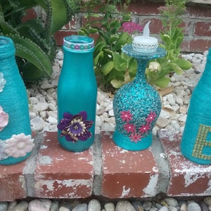 Repurposed 13.7 fluid ounces Frappuccino bottles painted aquamarine color spelling the word LOVE