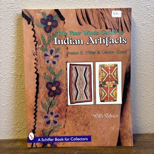 Może przedstawiać: Książka zatytułowana "The Four Winds Guide to Indian Artifacts" ze zdjęciami sztuki indiańskiej. Okładka jest brązowa z kwiatowymi koralikami i napisem "With Values". Książka Schiffer dla kolekcjonerów.
