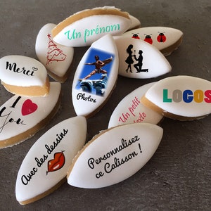 Puede incluir: Surtido de galletas en forma de almendra, blancas y beige, con varios diseños impresos en ellas. Algunos diseños incluyen un árbol de Navidad, una pareja, una foto, un corazón, una mariquita y las palabras "Merci", "Te amo", "Un prénom", "Photos", "Un petit texte", "Logos" y "Avec des dessins".