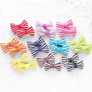 May include: Assortment of 12 pairs of colorful striped ribbon hair bows with white polka dots. Each bow is attached to a white alligator clip.