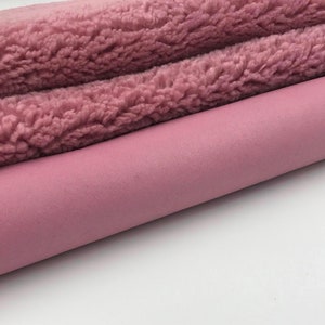 May include: Close-up of two rolls of fabric in shades of pink. The top roll has a fluffy, textured surface, while the bottom roll has a smooth, suede-like texture. The fabrics are likely for sewing or crafting projects.