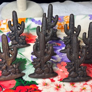 May include: A white ceramic mug with a black handle and the text "But First, Coffee" in a black, bold font. The mug is on a white surface.