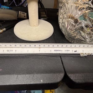 May include: A black leather choker necklace with a silver chain and clasp. The necklace is approximately 10 inches long. A small gold heart charm hangs from the choker. A ruler is placed next to the necklace.