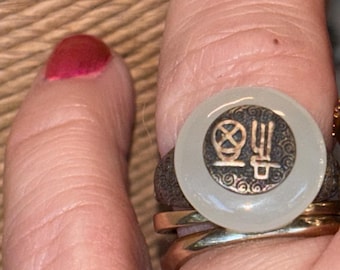 This is an adjustable sterling silver ring featuring a white jade or chalcedony stone with an engraved Chinese character for "Fu" (happiness
