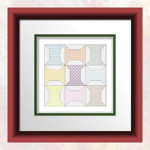 Op de afbeelding: Een ingelijst kruissteekontwerp met een herhalend patroon van kleurrijke spoelen garen. De spoelen zijn gerangschikt in een rasterpatroon, waarbij elke spoel een andere kleur en een ander patroon heeft. De lijst is een eenvoudige, rechthoekige lijst met een witte passe-partout.