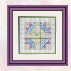 Op de afbeelding: Een ingelijst kruissteekontwerp met een geometrisch patroon in tinten blauw, groen en paars. Het ontwerp is op een witte achtergrond en ingelijst met een paarse lijst.