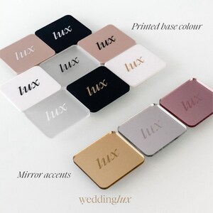 various colored square mirrors with the word "Lux" printed on them, arranged in a grid-like pattern.