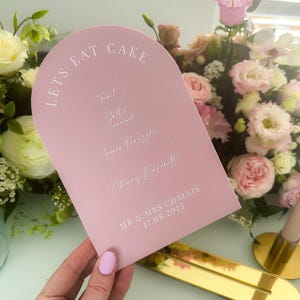hand holding pink dome cake sign