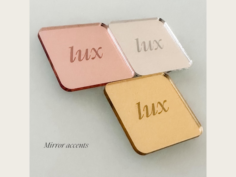 three square mirrors with the word "Lux" engraved on them, arranged in a triangular formation. Gold, Silver, Rose Gold