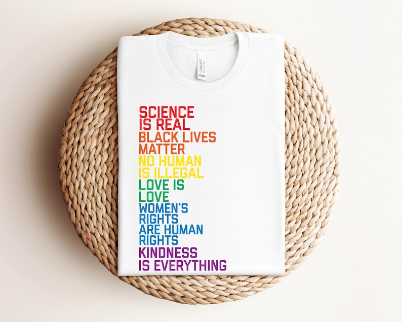 May include: White t-shirt with a rainbow-colored message that reads "Science is real, Black Lives Matter, No human is illegal, Love is love, Women's rights are human rights, Kindness is everything."