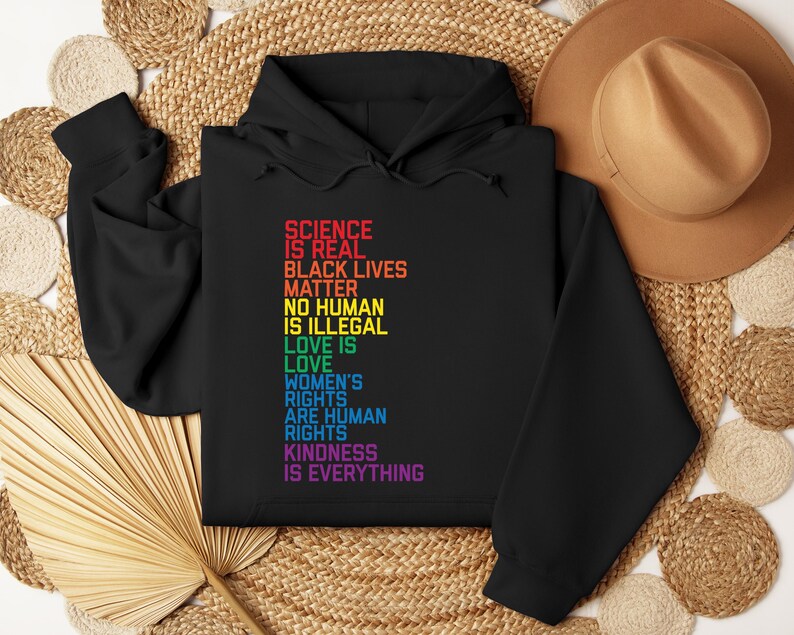 May include: Black hoodie with a rainbow-colored text print that reads "Science is real, Black Lives Matter, No Human is Illegal, Love is Love, Women's Rights are Human Rights, Kindness is Everything".