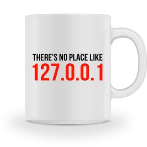 Könnte beinhalten: Weiße Keramik-Kaffeetasse mit schwarzem Text, der "There's no place like 127.0.0.1" in Rot lautet.