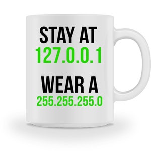 Könnte beinhalten: Eine weiße Keramiktasse mit schwarzem Text, der "STAY AT 127.0.0.1 WEAR A 255.255.255.0" lautet. Die Zahlen 127.0.0.1 sind grün.