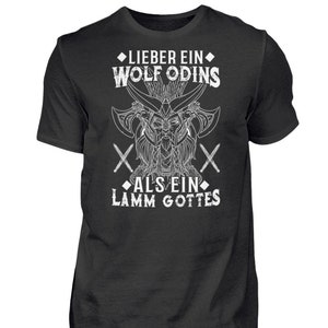 Könnte beinhalten: Ein schwarzes T-Shirt mit einem weißen Grafikdesign, das einen Wolfskopf mit Hörnern und den Text "Lieber ein Wolf Odins als ein Lamm Gottes" zeigt.