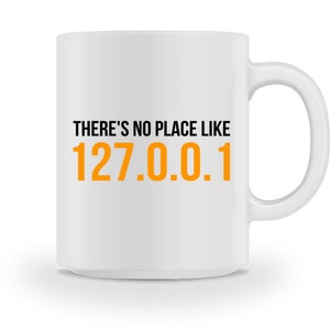 Könnte beinhalten: Weiße Keramik-Kaffeetasse mit schwarzem Text, der "THERE'S NO PLACE LIKE 127.0.0.1" in Orange lautet.